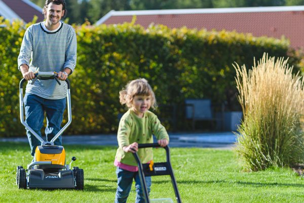 En pappa och dotter klipper gräs