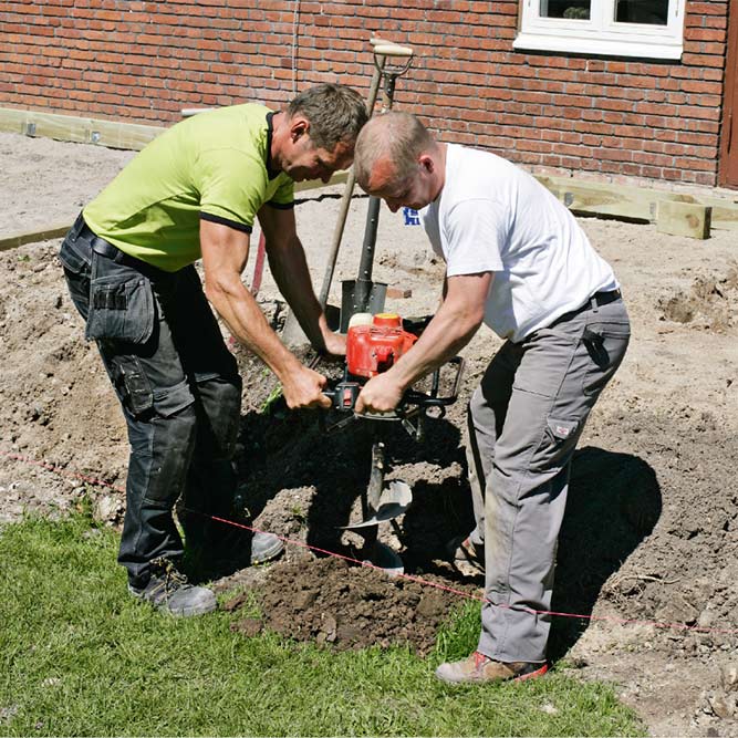 Hullene til stolpene graver vi med et 20 cm motorisert jordbor.