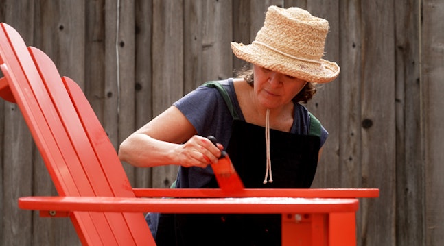 Kvinna målar stol trädgården