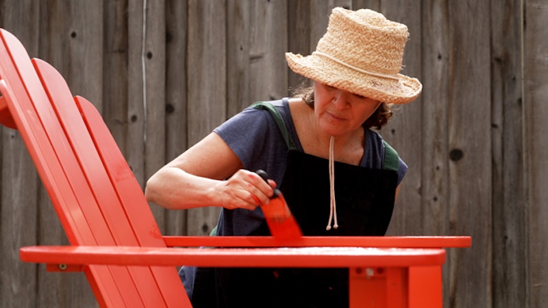 Kvinna målar stol trädgården