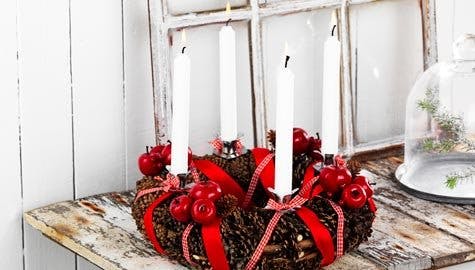 Adventskrans med kongler, røde epler og lys.