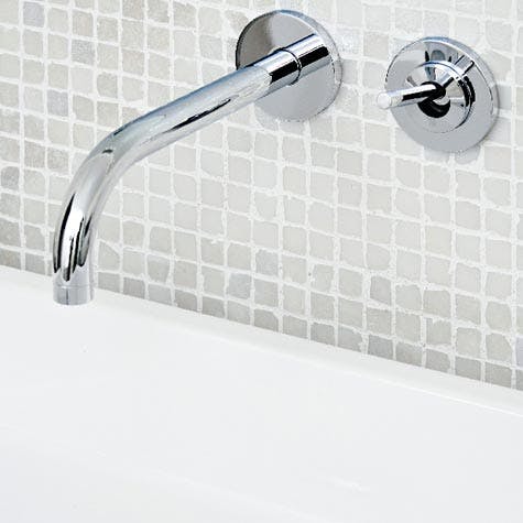 Veggen over servantene er dekket med glassmosaikk med innfelt armatur.
