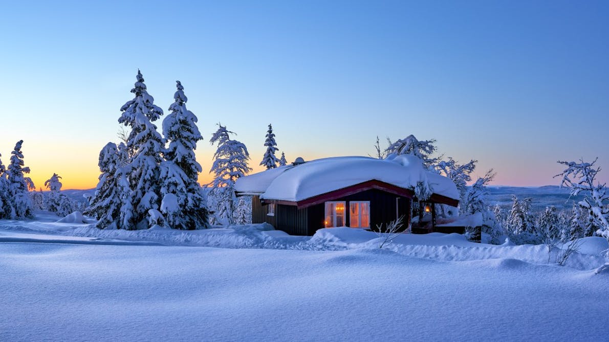 hytte på vinteren i solnedgangen