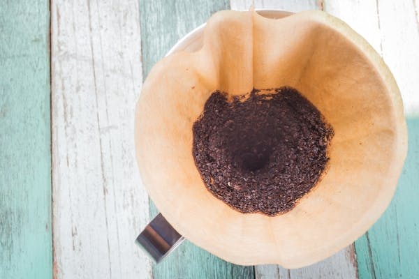 Kaffegrums i kaffefilter på bord