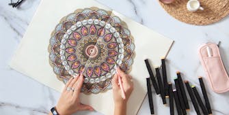Kvinde farvelægger en mandala-tegning hun har printet