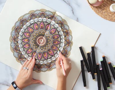 Kvinde farvelægger en mandala-tegning hun har printet